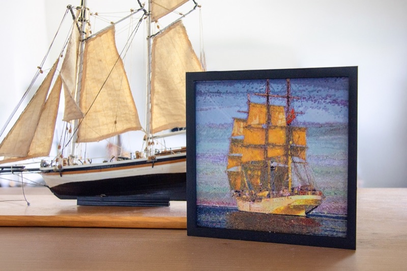 A framed tall ship print beside a model sailing ship